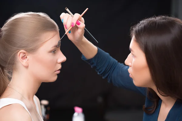 Maquillador haciendo maquillaje de una hermosa joven — Foto de Stock