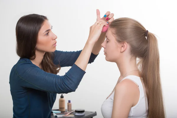 Maquillador haciendo maquillaje de una hermosa joven — Foto de Stock