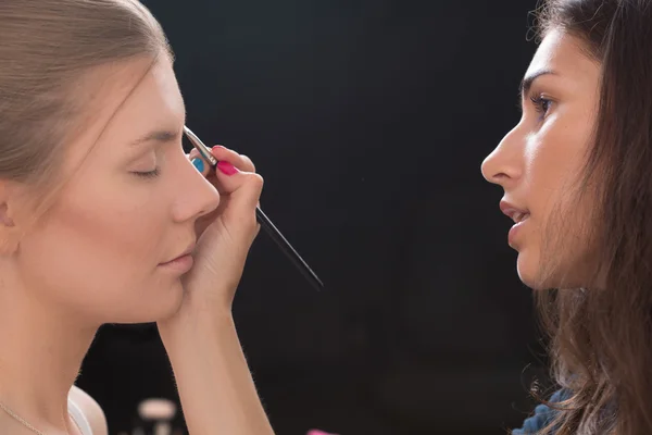 Maquillador haciendo maquillaje de una hermosa joven — Foto de Stock