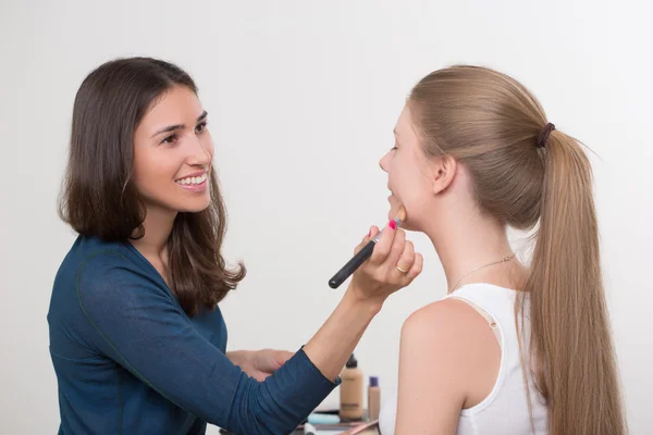 Maquillador haciendo maquillaje de una hermosa joven — Foto de Stock