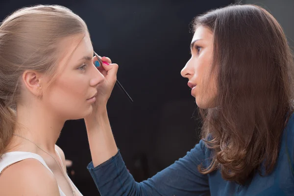 Maquillador haciendo maquillaje de una hermosa joven — Foto de Stock