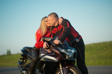 Motorcu adam ve bir motosiklet üzerinde oturan kadın.