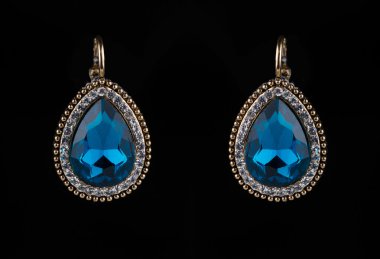 earring with colorful blue gems on black background