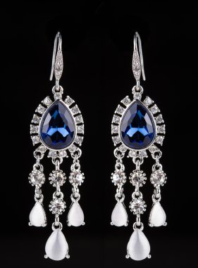 earring with colorful blue gems on black background