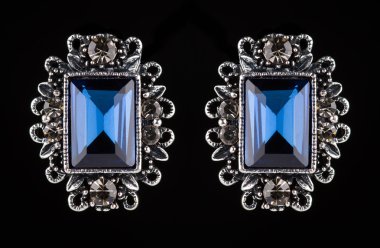earring with colorful blue gems on black background