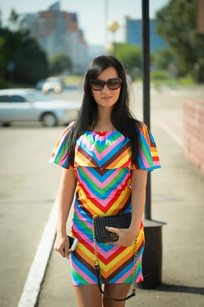 Fille en robe colorée et lunettes de soleil dans la rue — Photo