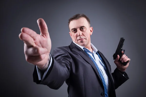 Man in a business suit with a gun — Stock Photo, Image