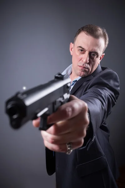 Мужчина в деловом костюме с пистолетом — стоковое фото