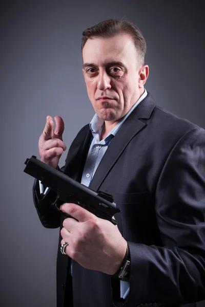 Man in a business suit with a gun — Stock Photo, Image