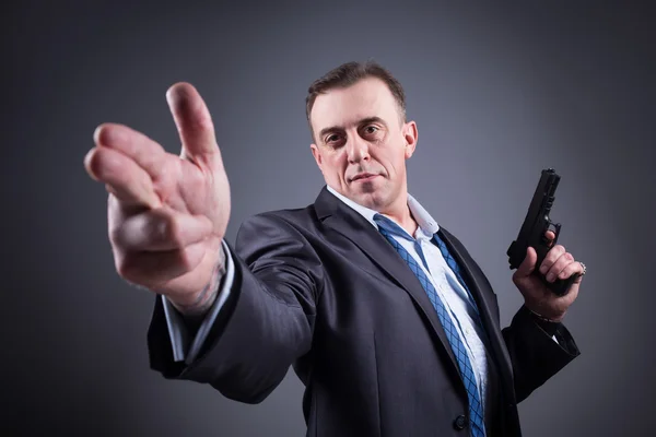 Un hombre con un traje de negocios con un arma — Foto de Stock