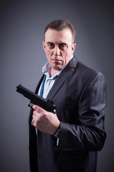 Man in a business suit with a gun — Stock Photo, Image