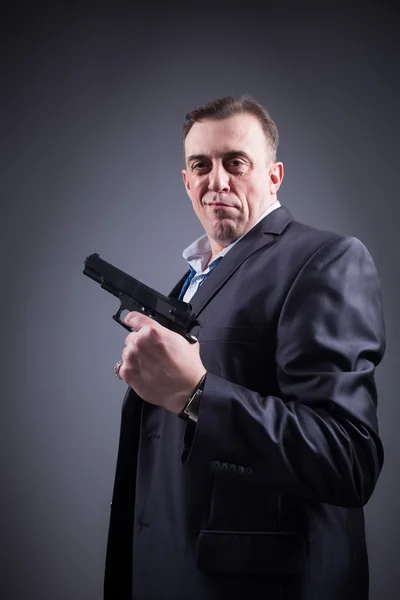 Man in a business suit with a gun — Stock Photo, Image