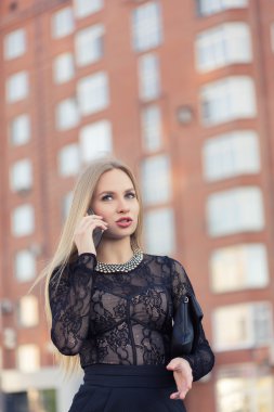 İş kadını sokakta cep telefonuyla konuşuyor.