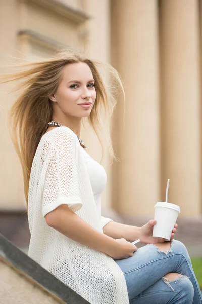 Stijlvolle vrouw drinken koffie te gaan in een stad straat — Stockfoto