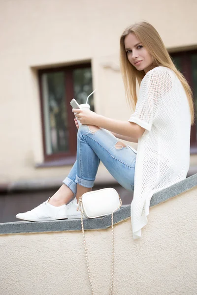 Stijlvolle vrouw drinken koffie te gaan in een stad straat — Stockfoto