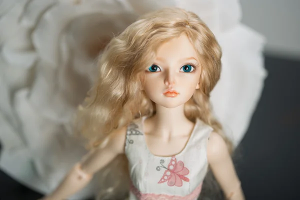 Hermosa muñeca sobre un fondo de flor artificial — Foto de Stock