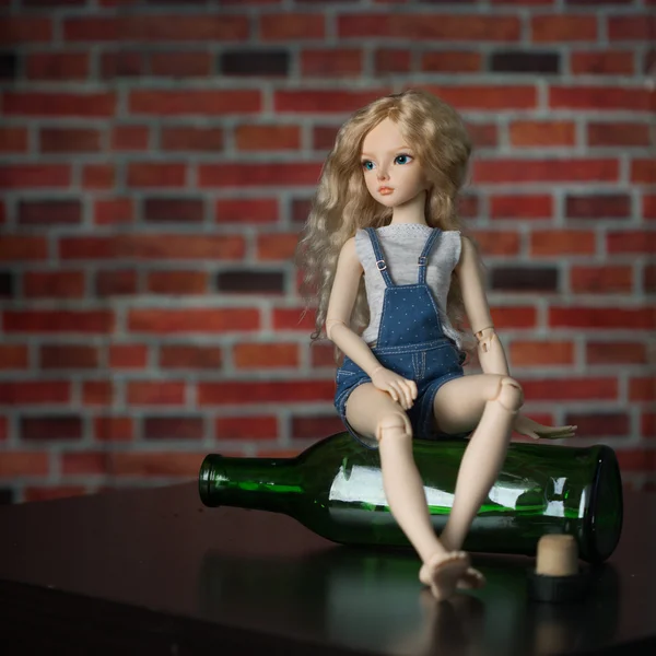 Boneca com uma garrafa. o conceito de alcoolismo — Fotografia de Stock