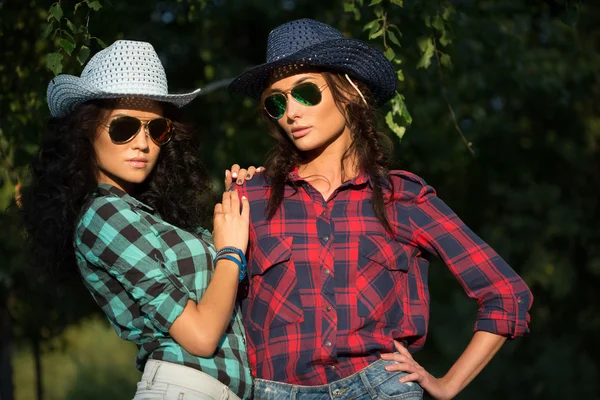 Menina sexy em chapéus de cowboy e camisas xadrez. óculos de sol — Fotografia de Stock