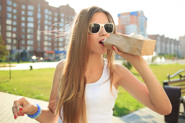 Meisje drinken uit een papieren zak in de straat. rookt — Stockfoto