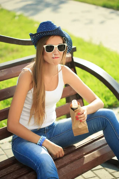 Meisje drinken uit een papieren zak in de straat. rookt — Stockfoto