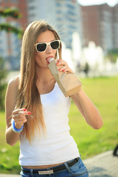 Meisje drinken uit een papieren zak in de straat. rookt — Stockfoto