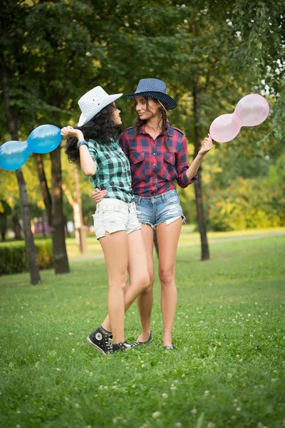 Twee meisjes in cowboy hoeden met ballonnen — Stockfoto