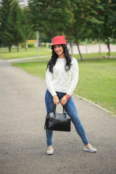 Niña en un sombrero rojo con orejas, sosteniendo una bolsa en la calle — Foto de Stock