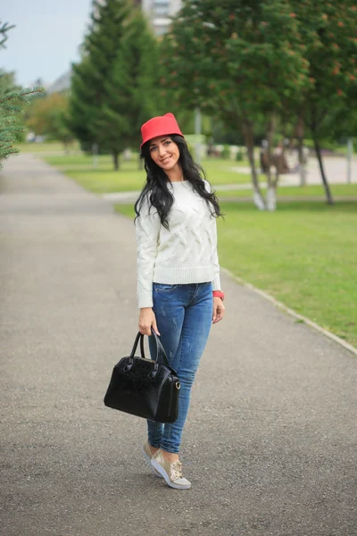 Niña en un sombrero rojo con orejas, sosteniendo una bolsa en la calle — Foto de Stock
