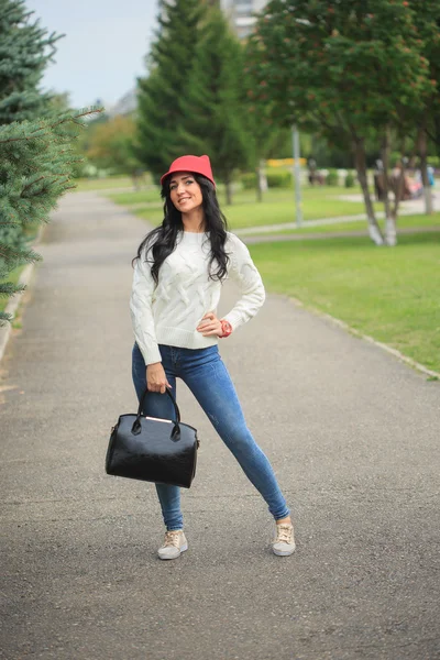 Flicka i en röd mössa med öron, hålla en väska på gatan — Stockfoto