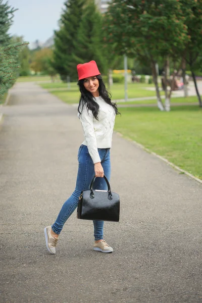 女孩在一顶红色的帽子，用耳朵，抱着一袋在大街上 — 图库照片
