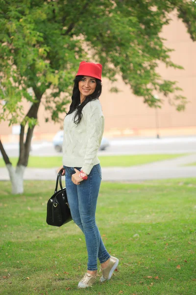 Niña en un sombrero rojo con orejas, sosteniendo una bolsa en la calle — Foto de Stock