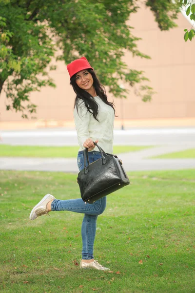 Девушка в красной шляпе с ушами, держащая сумку на улице — стоковое фото