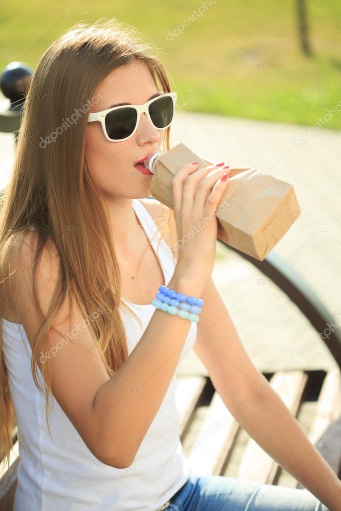 girl drinks from a bottle in a paper bag. 