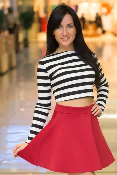 Chica en una blusa a rayas camina alrededor de la tienda . — Foto de Stock