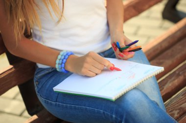 bir parkta bir bankta oturan genç kız boya