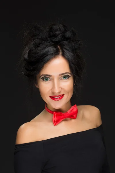 Girl with a complicated hairdo on a black background. Red bow tie — Stock Photo, Image