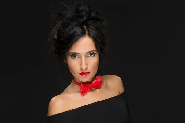 Meisje met een ingewikkelde kapsel op een zwarte achtergrond. Red bow tie — Stockfoto