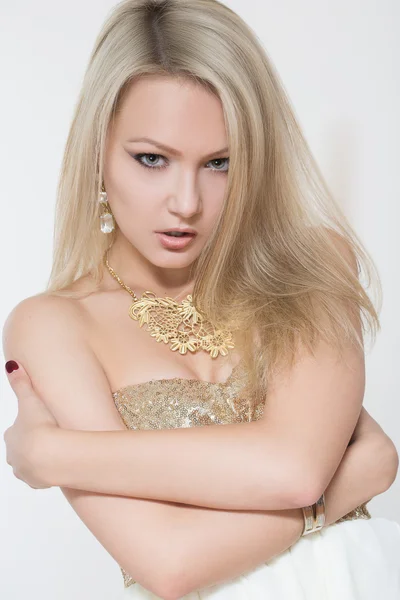 Beautiful young blonde girl. in a gold necklace and dress — Stock Photo, Image