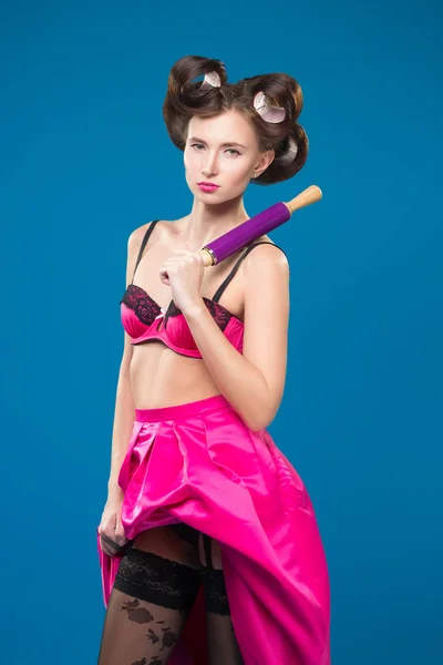 Sexy young housewife standing with a rolling pin in her hand. — Stock Photo, Image
