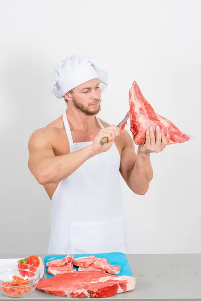Szakács testépítő nagy darabokban, a nyers hús előkészítése. — Stock Fotó