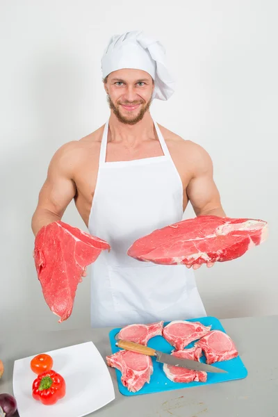 Chef-kok bodybuilder voorbereiding van grote brokken van rauw vlees. — Stockfoto