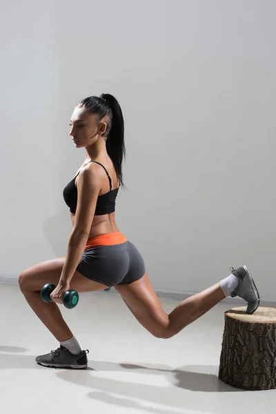 Giovane, bella, ragazza atletica esegue squat con manubri in una palestra . — Foto Stock