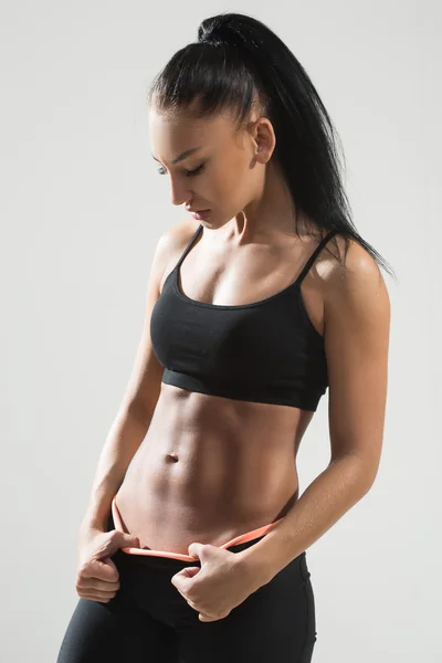 Krásná atletická žena ukazující svaly na tmavém pozadí — Stock fotografie