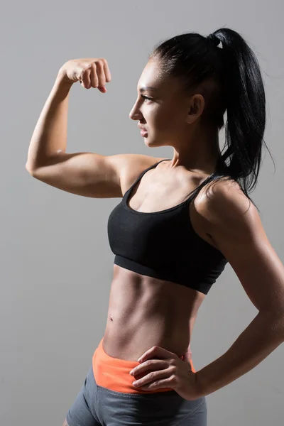 Retrato de jovem mulher fitness mostra bíceps . — Fotografia de Stock