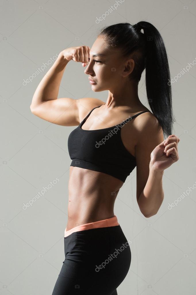 Portrait of young fitness woman shows biceps. Stock Photo by