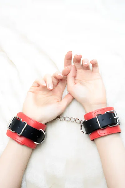 Female hands in leather handcuffs. on the background sheet. sex toys. — Stock Photo, Image
