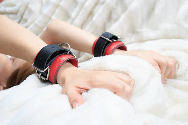 Female hands in leather handcuffs. eagerly grabbed the sheets.. sex toys. — Stock Photo, Image