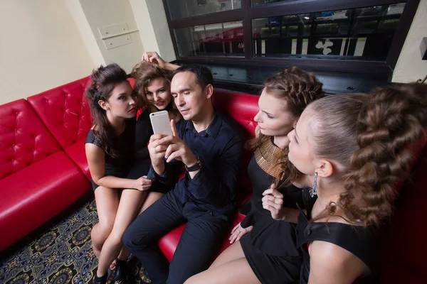 A man holding a cell phone. next four girls. — Stock Photo, Image