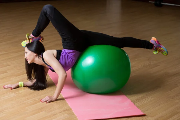 Фитнес-женщина в спортзале отдыхает на пилатесе. Молодая женщина делает упражнения на фитнес-мяч . — стоковое фото