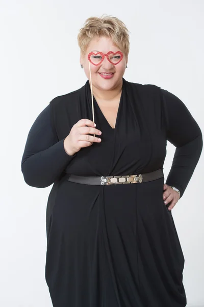 Mujer gorda sonriente sosteniendo gafas en forma de corazones — Foto de Stock